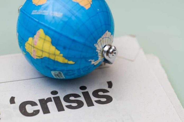 A small globe resting on a newspaper with the word 'crisis'