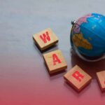 A small globe next to wooden blocks spelling 'WAR' with a warning symbol