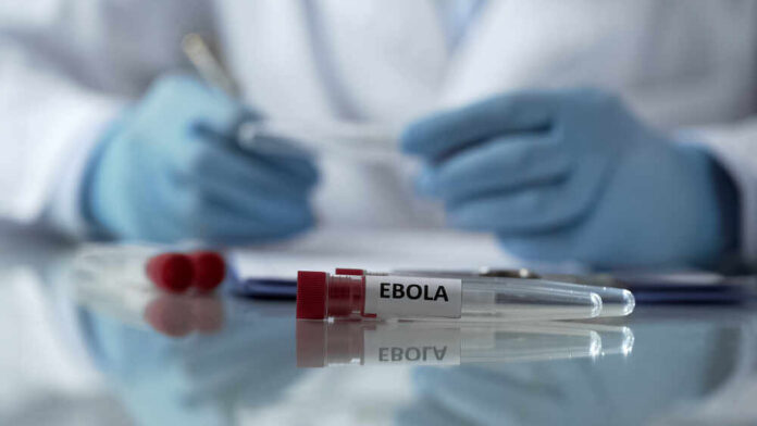 Ebola test tubes on lab table with gloved scientist in background