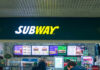 Subway restaurant sign with menu displays in the background