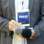 Trump Drops ‘Dishonest’ Bomb On Reporter Journalist with press badge, notebook, and microphones.