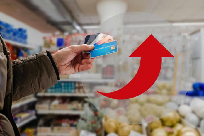 Hand holding credit cards with red upward arrow
