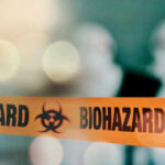 Biohazard tape with blurred figures in background.