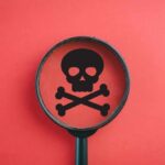 Baby Food POISONED — Extortion Plot Magnifying glass focusing on a skull and crossbones symbol against a red background