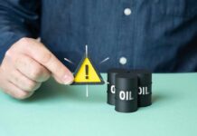 A person holding a warning sign next to oil barrels