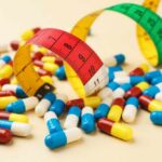 Colorful pills scattered around measuring tapes