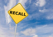 Yellow sign with RECALL text against blue sky.