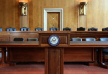 Senate’s Pay Docking: Real Change or Facade? Empty Senate chamber with a wooden podium and chairs