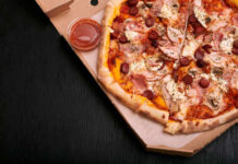 A pizza with various toppings in a delivery box