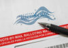 Judge Freezes Voter Purge Engine Vote-by-mail envelope with pen on top.