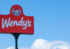 Wendy's restaurant sign against a clear blue sky