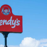 Wendy's restaurant sign against a clear blue sky