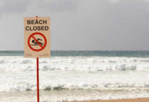 Coast Guard Can’t Find Her – Now What? Sign indicating the beach is closed with a no swimming symbol