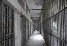 Empty prison corridor with barred cells on either side