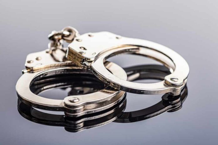 Close-up of metallic handcuffs on a reflective surface