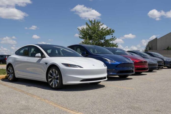 A lineup of Tesla electric vehicles parked outdoors under a blue sky