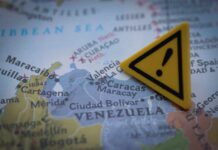 A close-up of a map showing Venezuela with a yellow warning sign