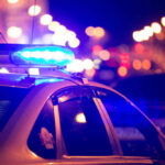 Police car with flashing blue lights at night.