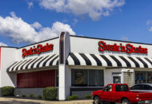 Steak 'n Shake restaurant exterior with striped awnings and parked vehicles