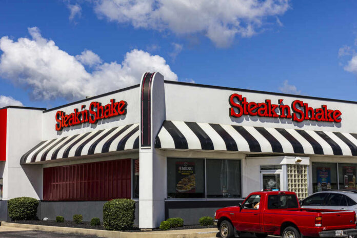 Steak 'n Shake restaurant exterior with striped awnings and parked vehicles