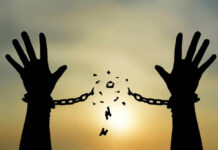 Silhouetted hands breaking chains against sunset sky.