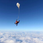 Skydiver descending through clouds with a parachute