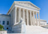 Supreme Court building with columns, fountain, and statue.