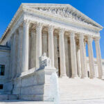 Supreme Court building with columns, fountain, and statue.