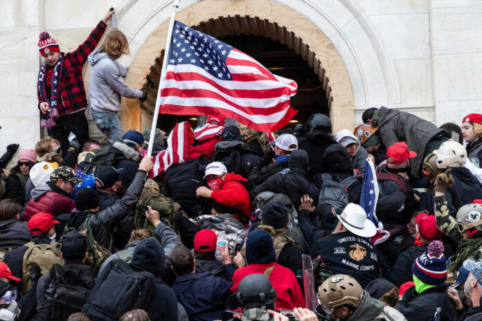 Crowd storming a building, waving an American flag.