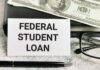 A sign reading 'Federal Student Loan' next to a stack of money and a pen