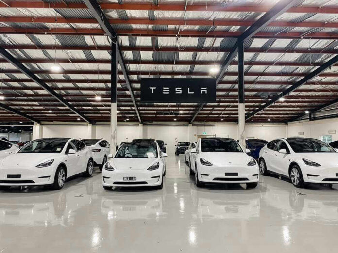 White Tesla cars displayed in showroom with Tesla sign.