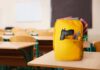 A yellow backpack with a gun partially visible in a classroom setting