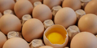 Eggs in carton one cracked revealing yolk