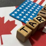 Wooden blocks spelling 'TARIFFS' on flags of Canada and the USA