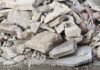 People examining rubble of collapsed building in sunlight.
