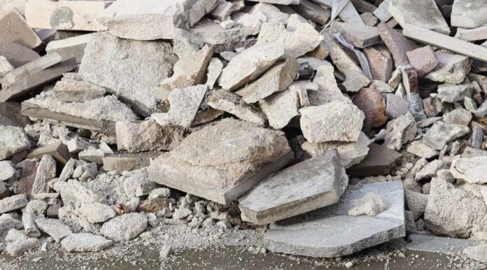 People examining rubble of collapsed building in sunlight.