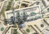 A stack of hundred dollar bills secured with a chain and padlock
