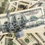 A stack of hundred dollar bills secured with a chain and padlock