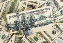Tax Dollars Sent To Dead? Not Anymore! A stack of hundred dollar bills secured with a chain and padlock