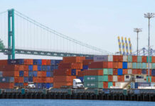 Trade Bombshell: USMCA Put On Ice A view of stacked shipping containers at a port with a bridge in the background