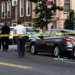 Police and crime scene tape on city street.