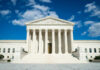 Supreme Court building with grand columns and steps under a blue sky