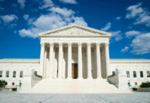 Supreme Court building with grand columns and steps under a blue sky
