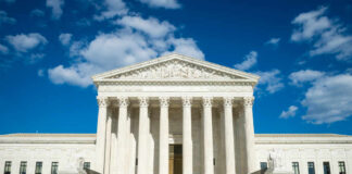 Supreme Court building with grand columns and steps under a blue sky