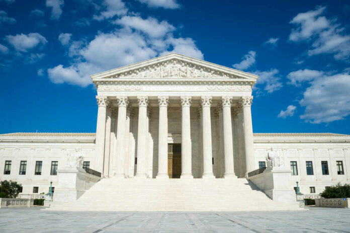 Supreme Court building with grand columns and steps under a blue sky