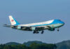 Airplane flying above trees with blue sky background