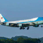 Air Force One Decoy? Iran Whisper Sparks Switch Airplane flying above trees with blue sky background