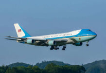 Air Force One Decoy? Iran Whisper Sparks Switch Airplane flying above trees with blue sky background