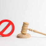 Wooden judge's gavel beside a red prohibition symbol