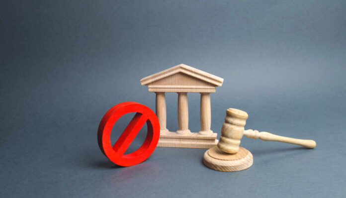 Wooden courthouse with red prohibition symbol and judge’s gavel
